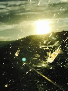 A photograph of the sun seen through a dirty, scraped glass.
