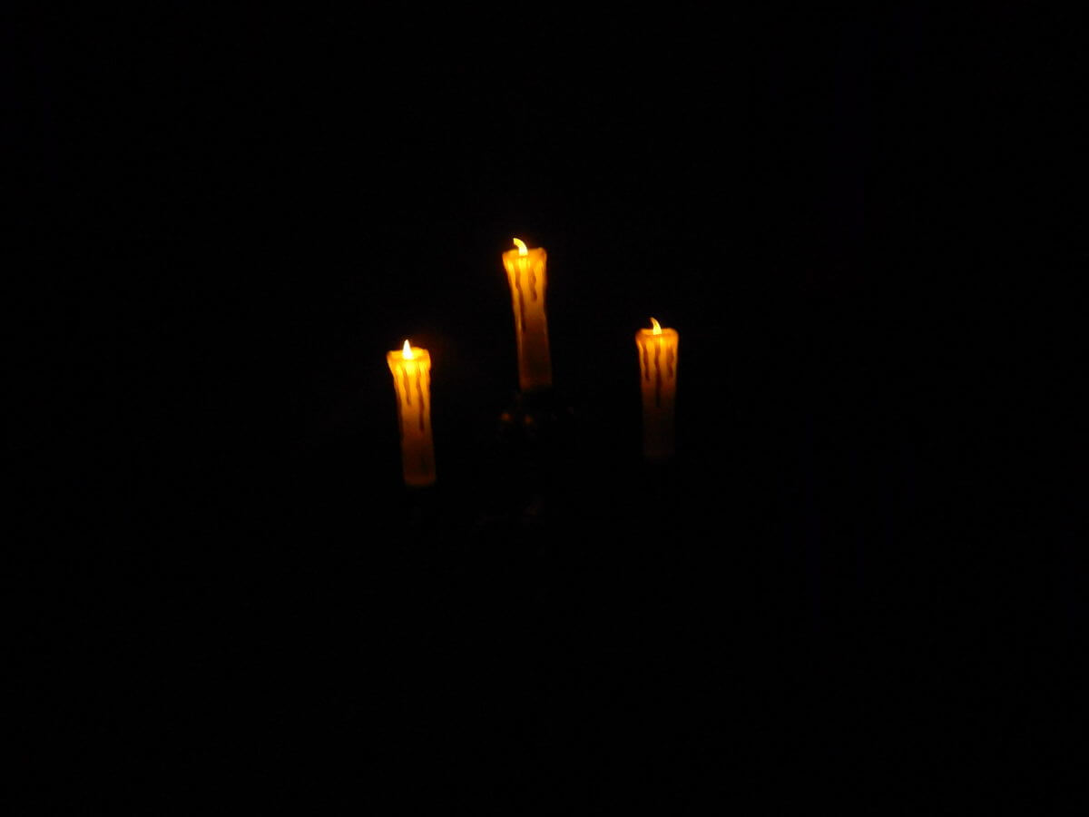 A photograph of three candles in the dark.