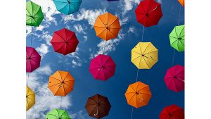 A photograph of brightly coloured umbrellas, strung in the sky.
