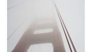 A photograph of a bridge disappearing into fog.