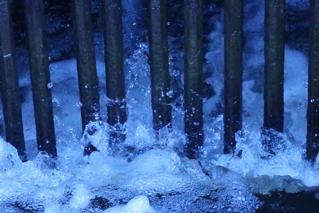 A close-up photograph of water rushing between metal bars.
