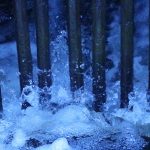 A close-up photograph of water rushing between metal bars.