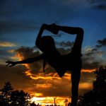 A photograph of a dancer silhouetted against the sunset sky.