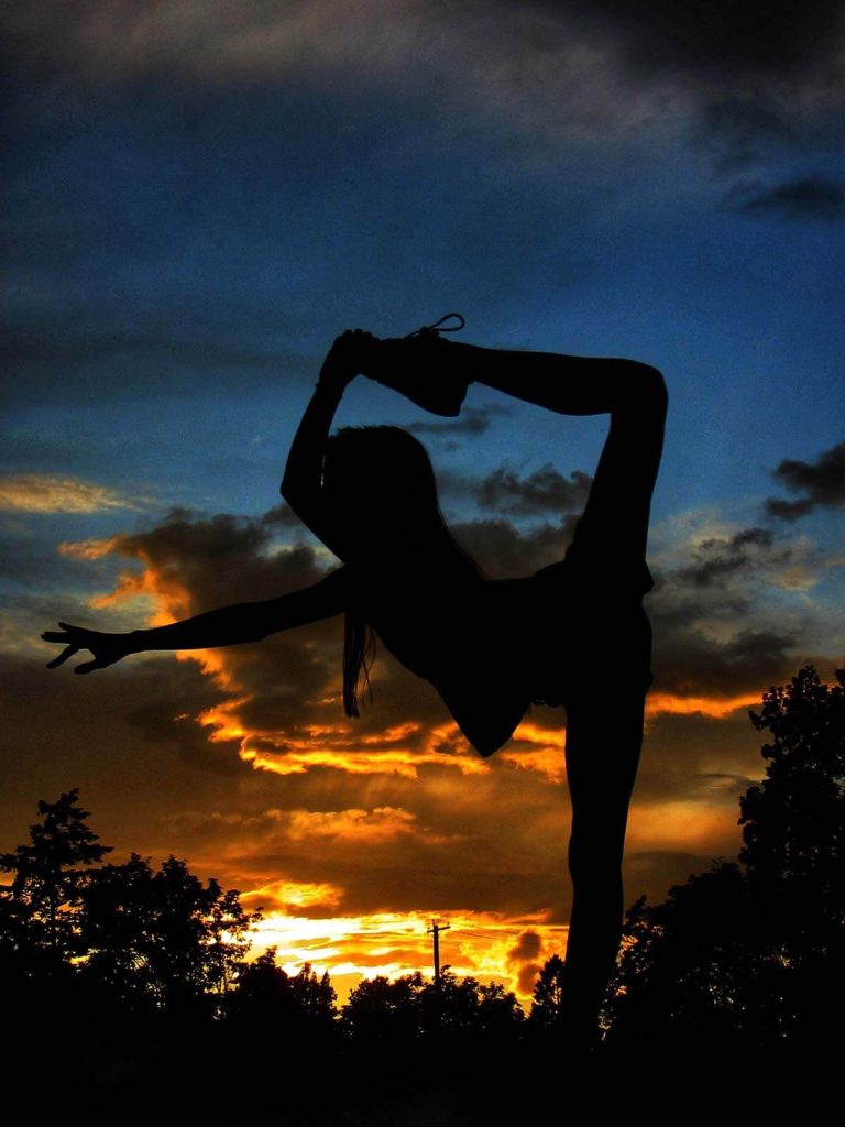 A photograph of a dancer silhouetted against the sunset sky.