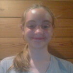 Headshot of Tilly Marlow, against brown wooden wall.