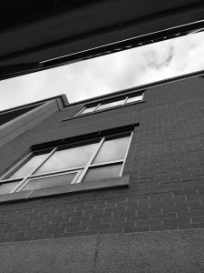 Black and white photograph of a brick building with windows from below